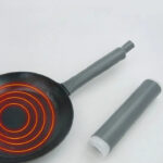 Futuristic heat-resistant handle sleeve next to a black frying pan with a glowing red spiral pattern indicating heat